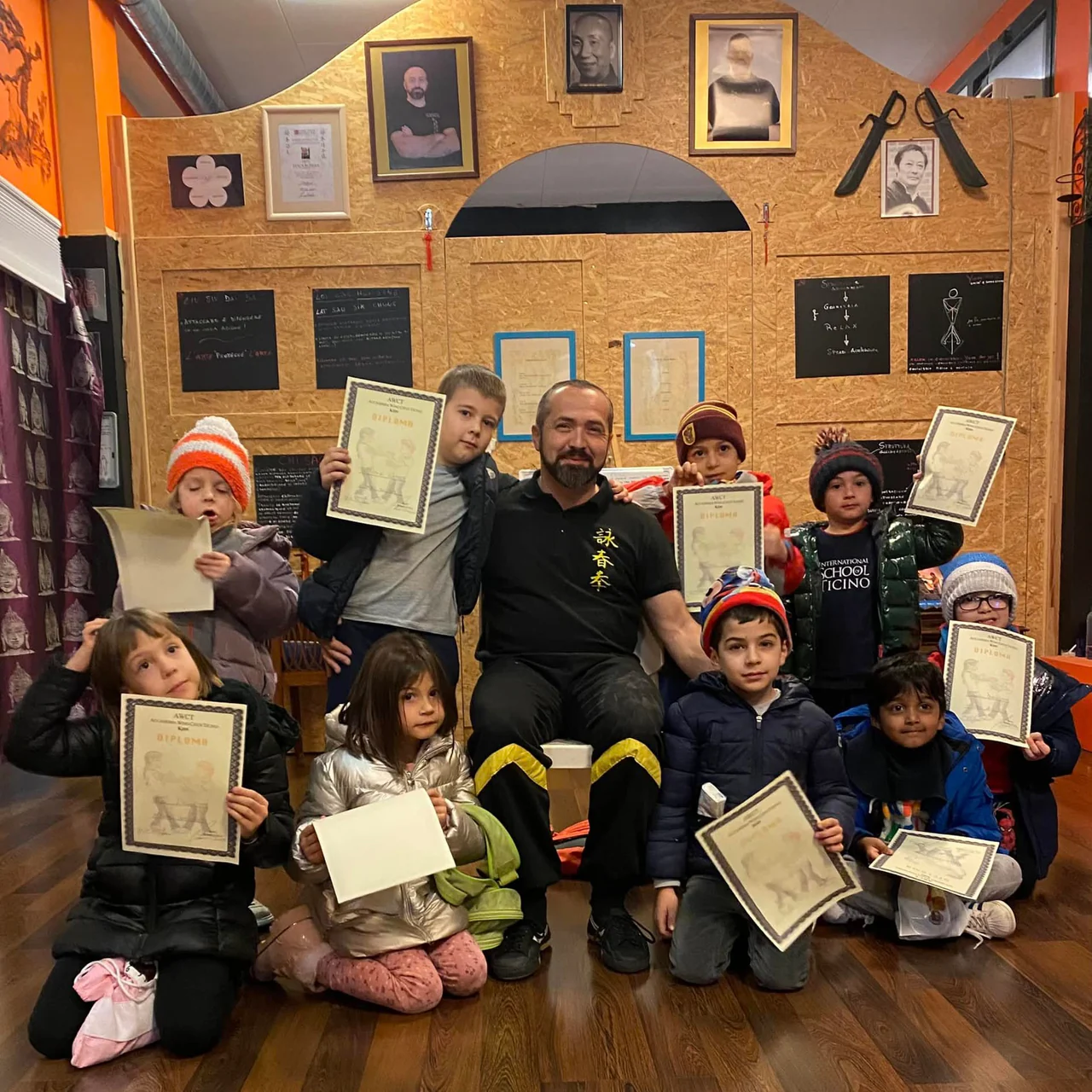 I bambini mostrano gli attestati, seduti attorno a Sifu Luca Bomba